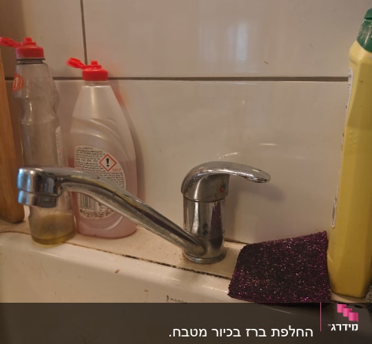 ברז כיור עם חומרי ניקוי וספוג קרצוף